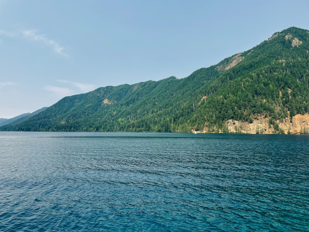 green mountain beside body of water during daytime