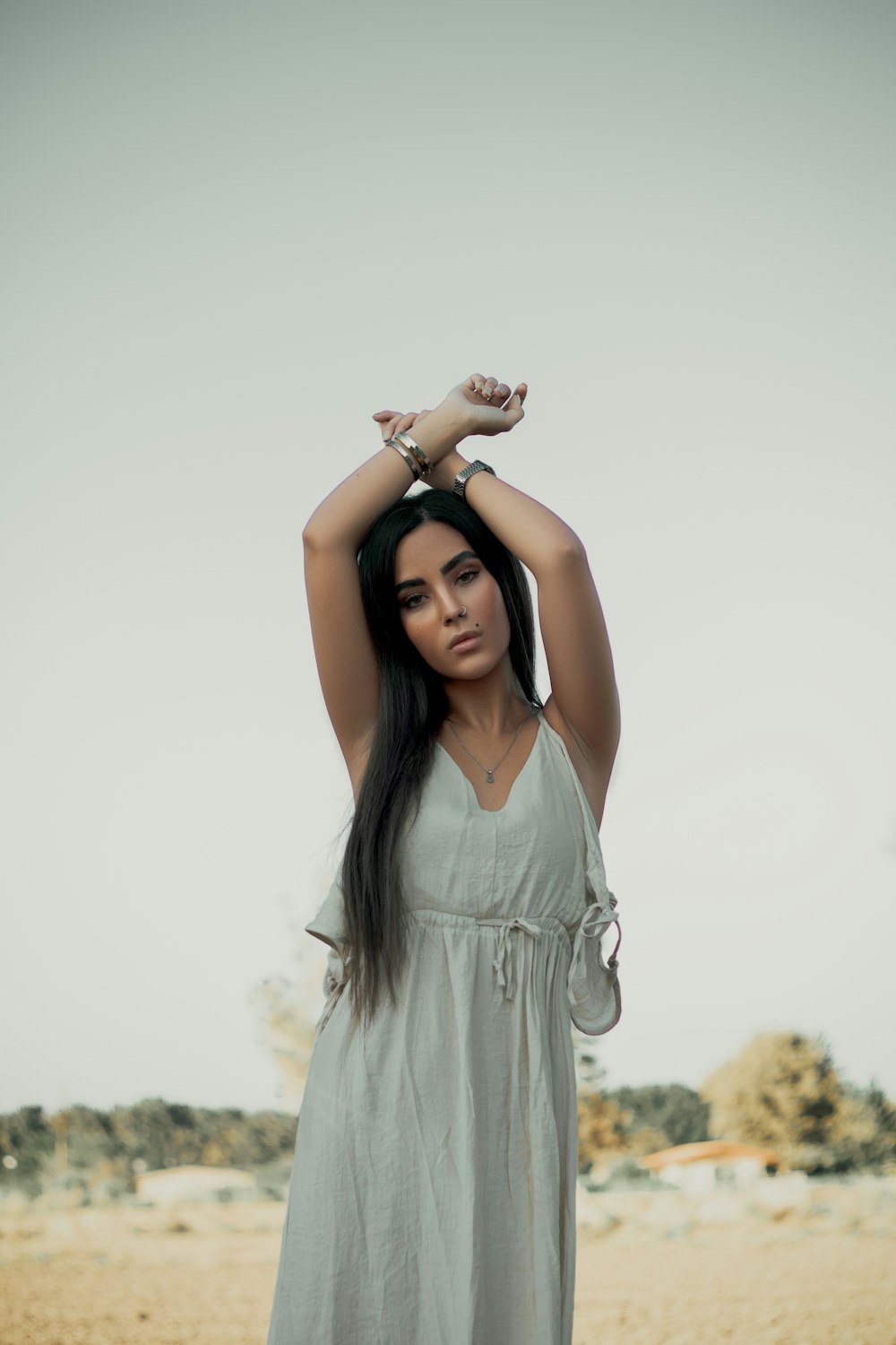 mujer con vestido gris sosteniendo su cabello