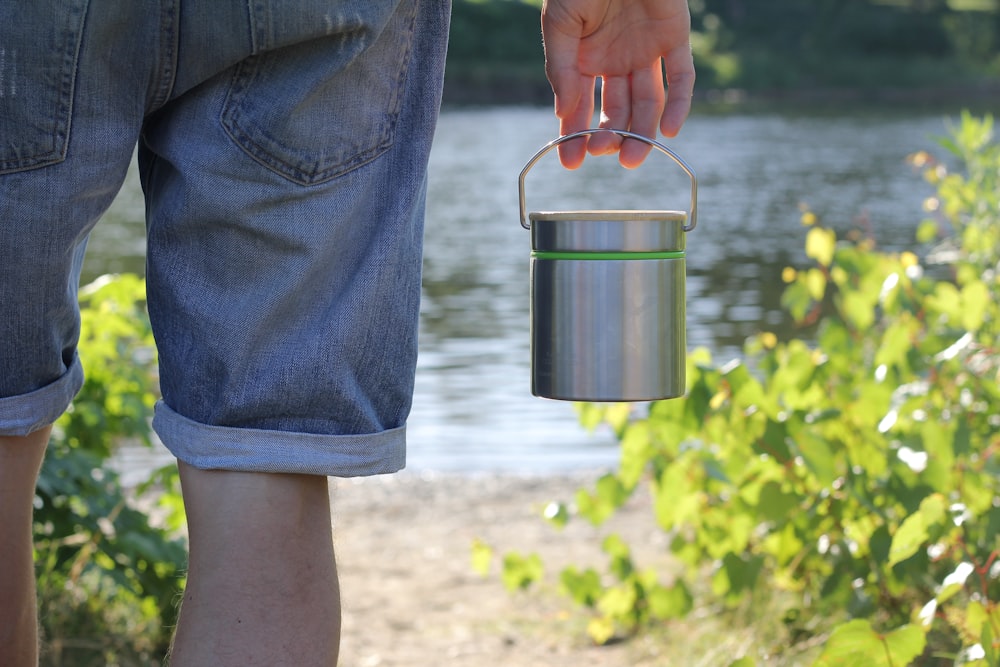 person in blue denim jeans holding stainless steel bucket