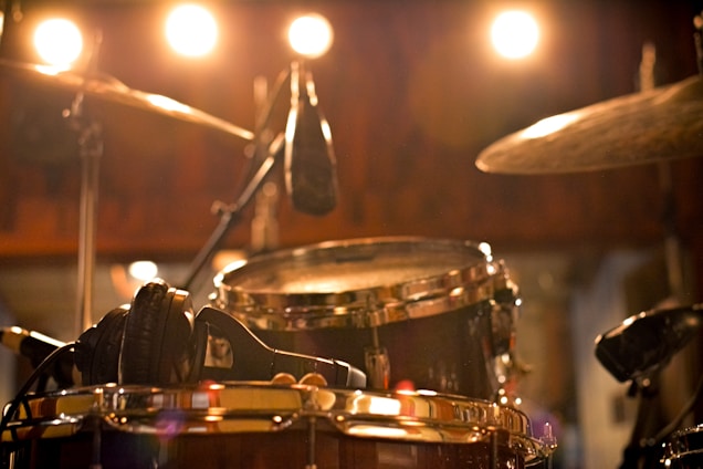 A warm portrait of the drum teacher smiling beside a drum kit in a cozy, sunlit studio.