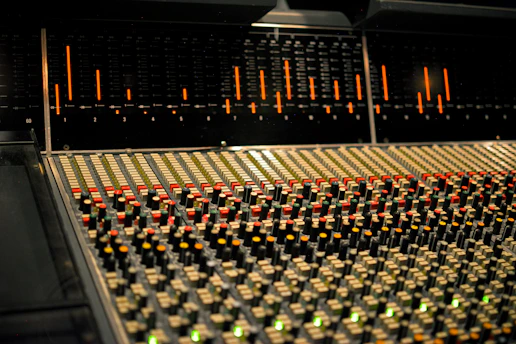 Professional audio mixing console with colorful lights in a dim studio.