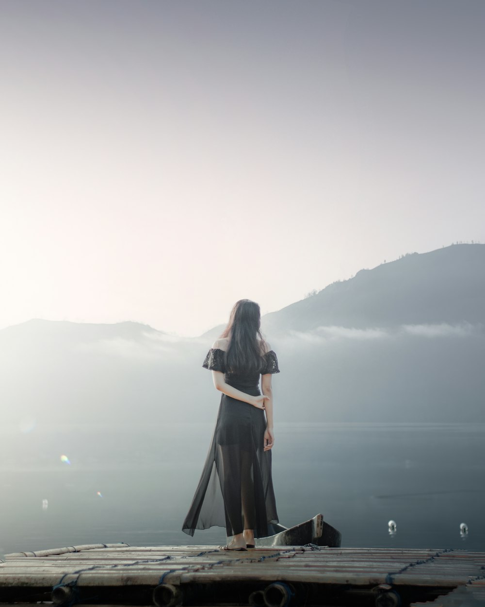 woman in black dress standing on brown wooden dock during daytime