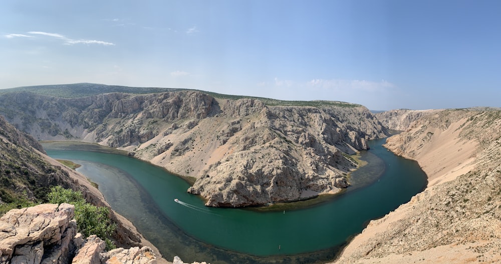 green lake between brown mountains under blue sky during daytime