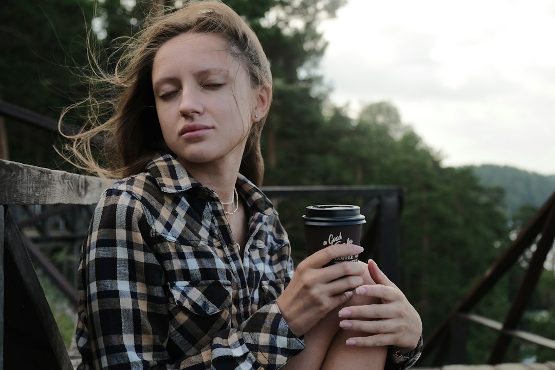 woman in black and white plaid dress shirt holding black cup