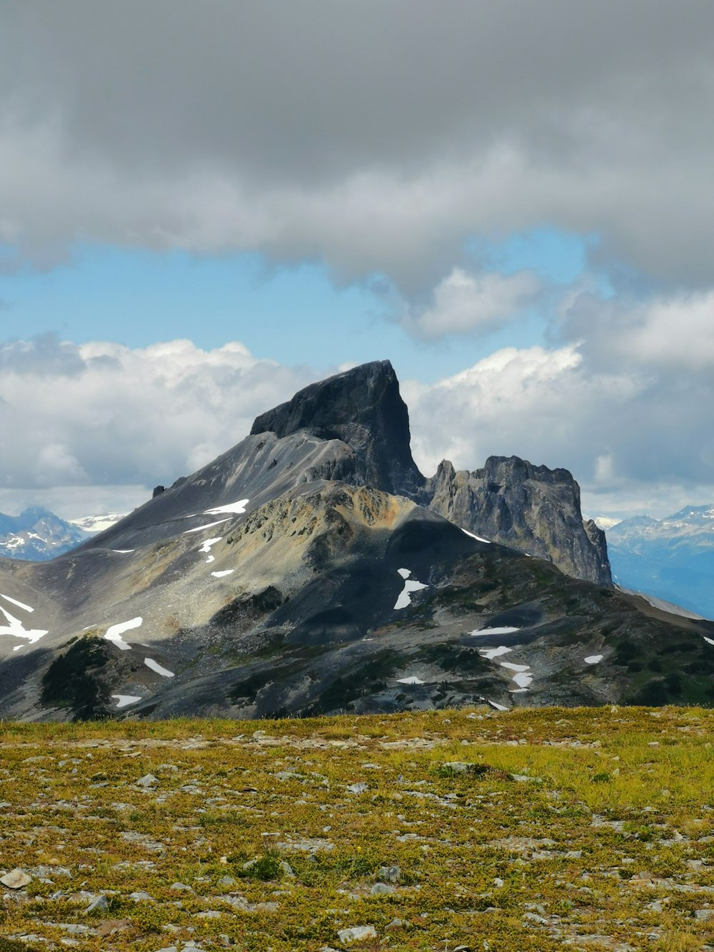 green grass field near snow covered mountain under white clouds during daytime