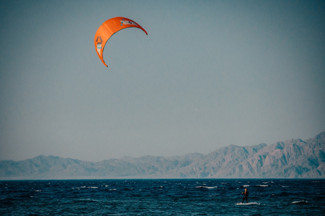 person in orange parachute over the sea during daytime