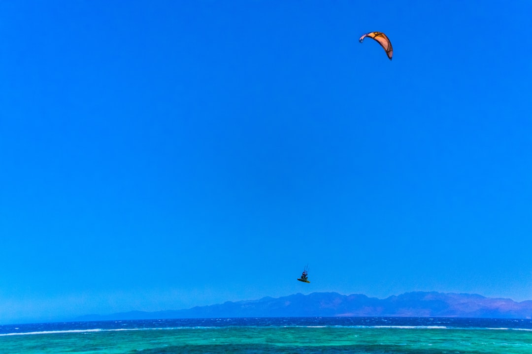 person in black and white shorts surfing on blue sea under blue sky during daytime