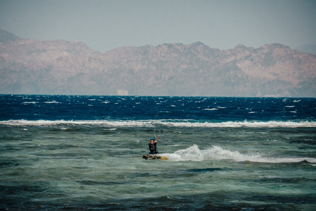 person in yellow and black wetsuit riding yellow kayak on sea during daytime