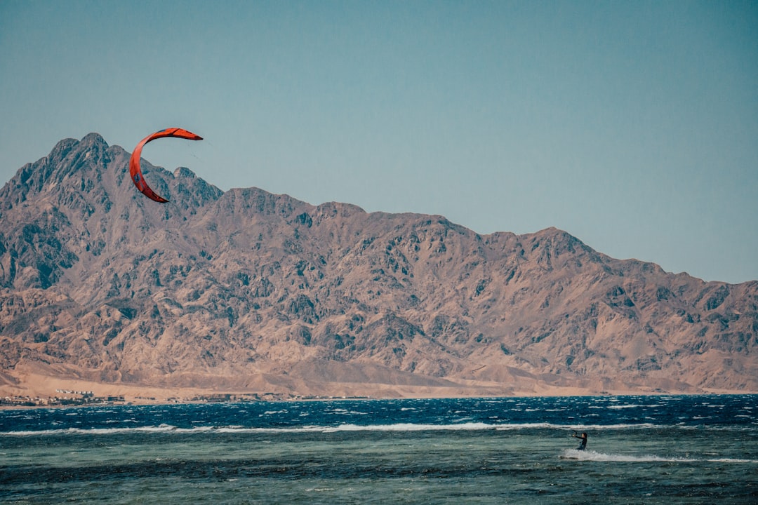 person surfing on sea near mountain during daytime