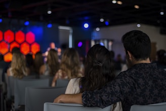 man in black and gray plaid dress shirt sitting beside woman in white shirt