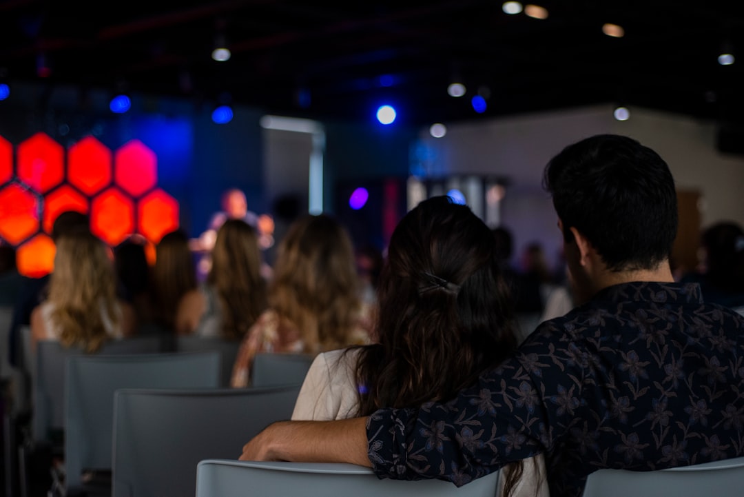 man in black and gray plaid dress shirt sitting beside woman in white shirt