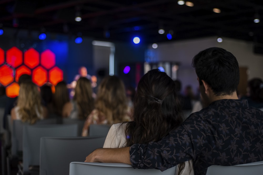 man in black and gray plaid dress shirt sitting beside woman in white shirt