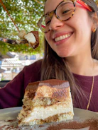 A woman enjoying a healthy dessert, smiling in a bright, cozy kitchen.