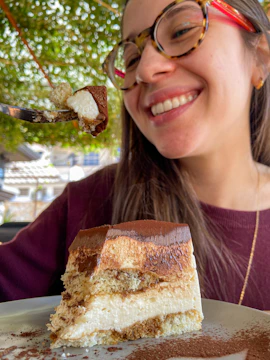 A woman enjoying a healthy dessert, smiling in a bright, cozy kitchen.