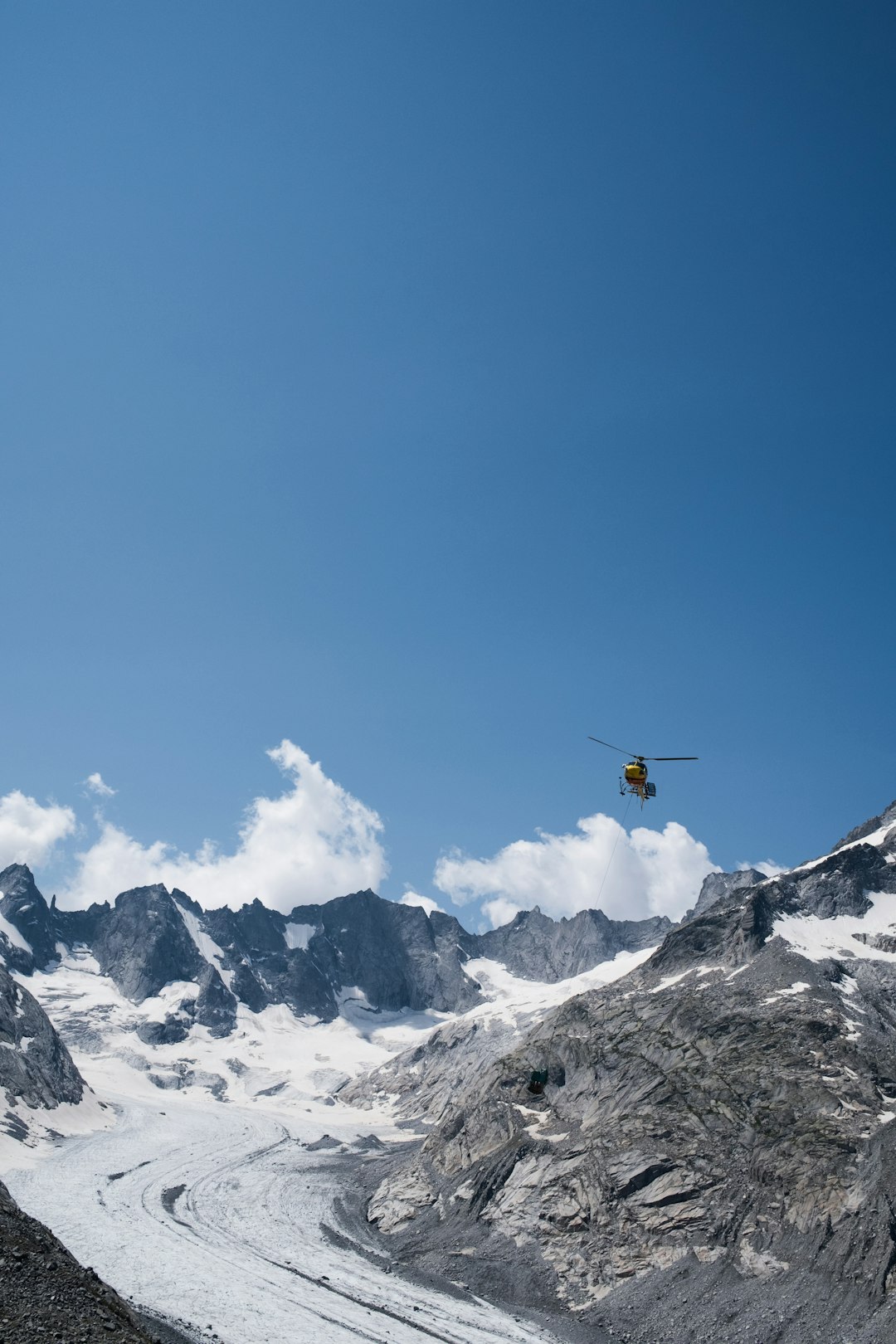 orange and black helicopter flying over snow covered mountain during daytime