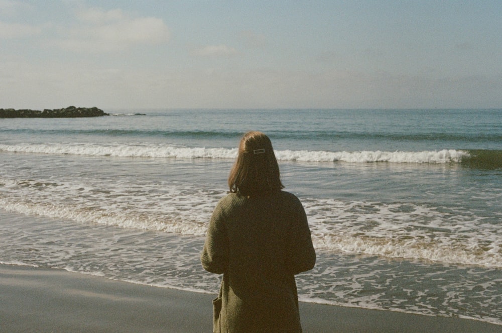 woman in brown coat standing on beach during daytime