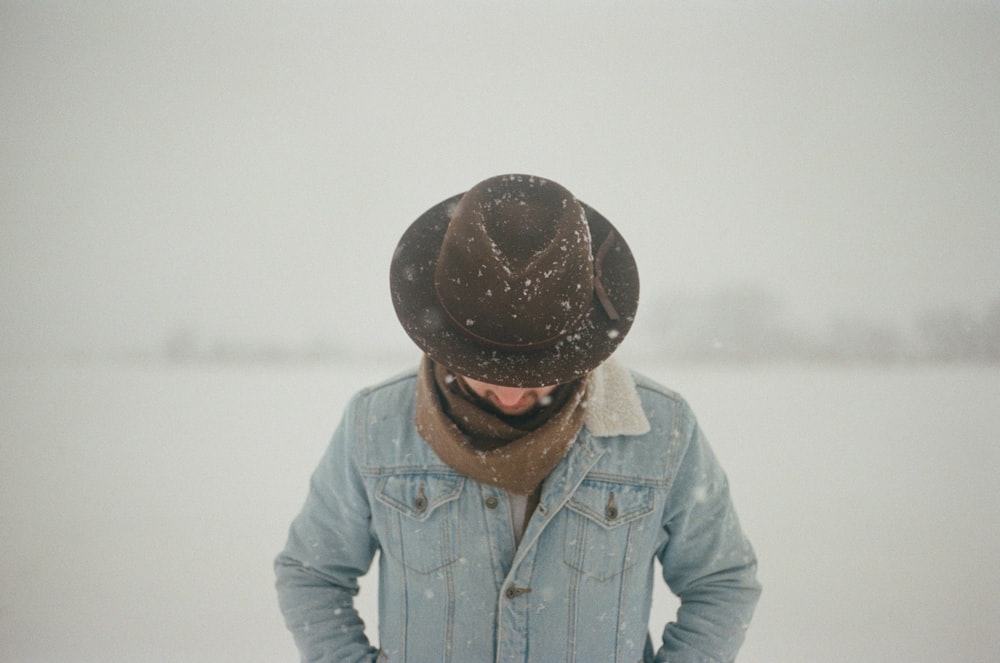 man in blue denim jacket wearing brown hat