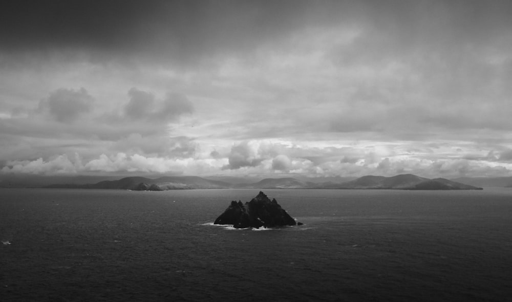 grayscale photo of rock formation on sea