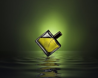 gold colored and black perfume bottle on water