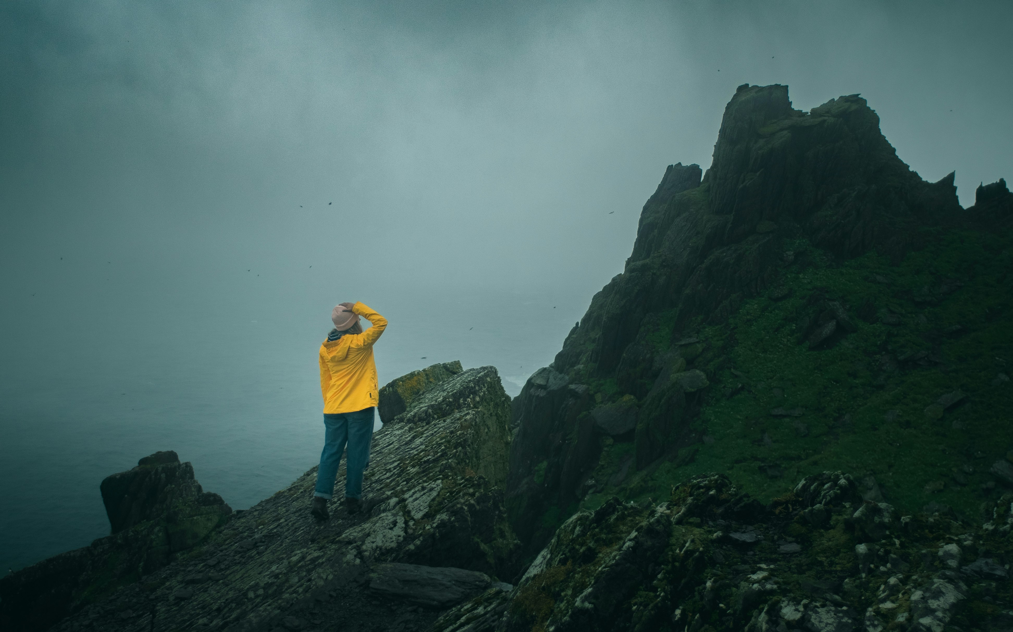 man in yellow shirt standing on rock formation