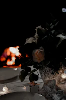 A softly lit romantic garden table with dark floral arrangements and candles at dusk.
