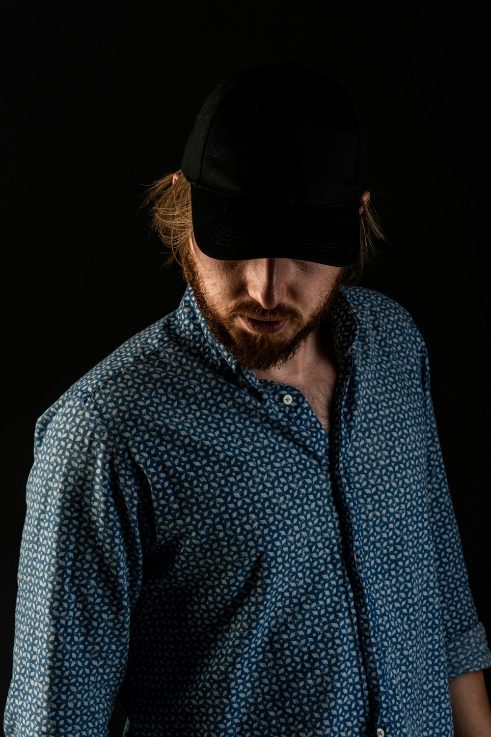 man in blue and white button up shirt wearing black cap