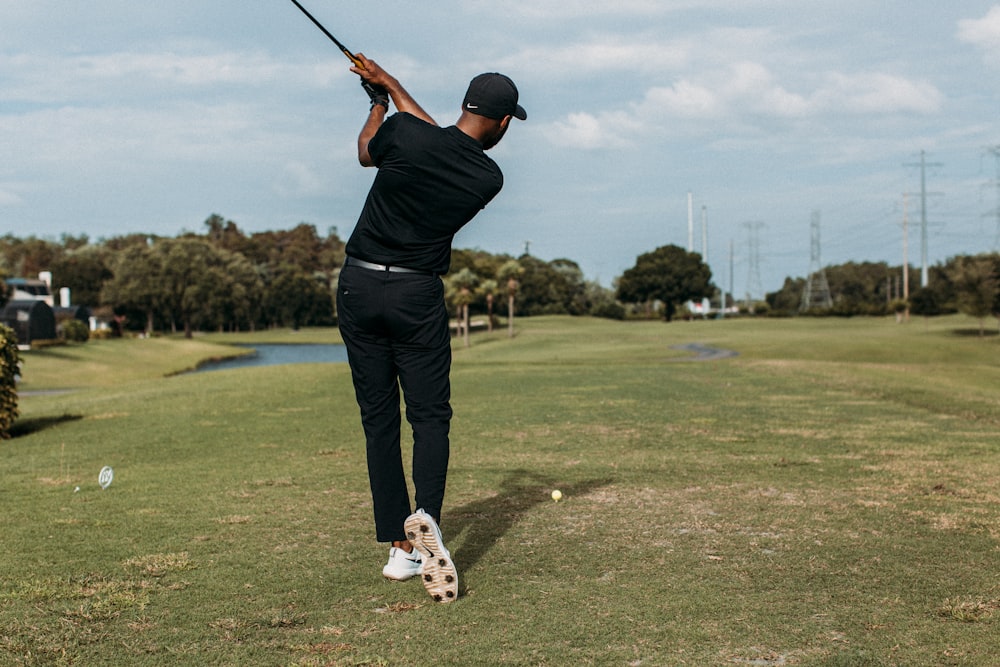 man in black shirt and black pants playing golf during daytime