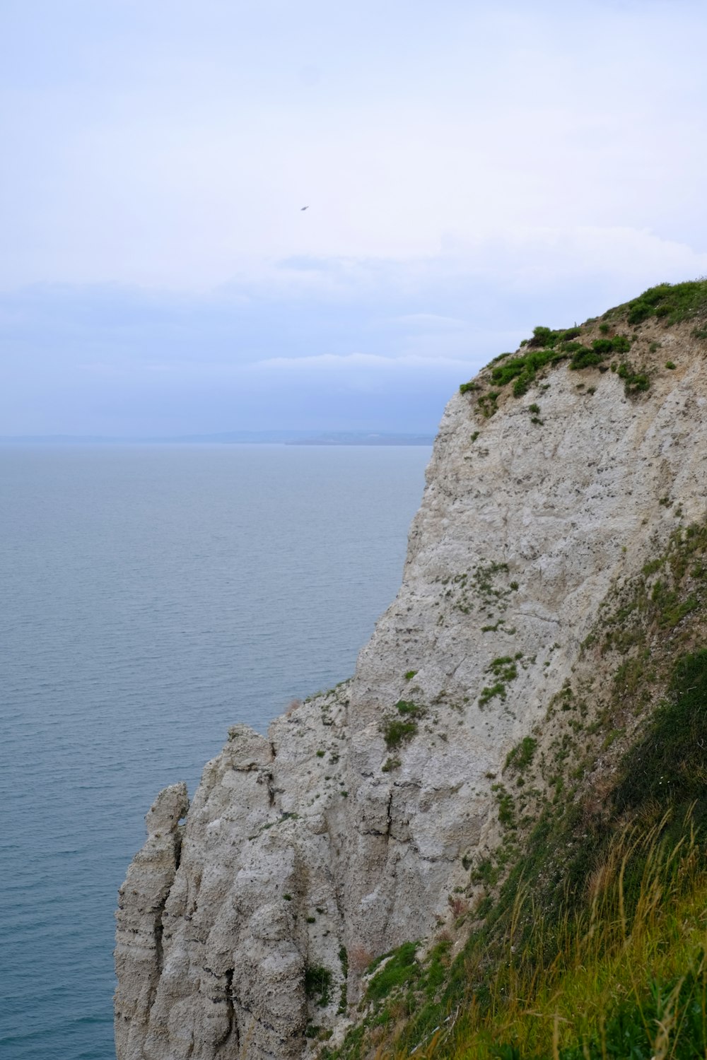 Montagne Rocheuse grise au bord de la mer bleue pendant la journée