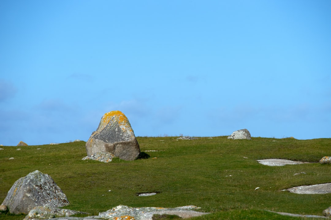 gray rock formation on green grass field under blue sky during daytime