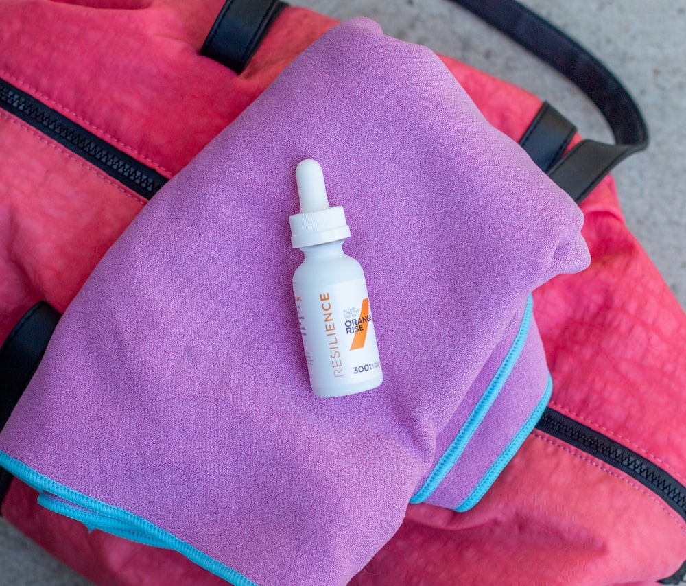 white plastic bottle on purple textile