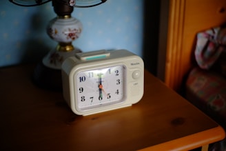 A digital clock radio displaying time on a bedside table