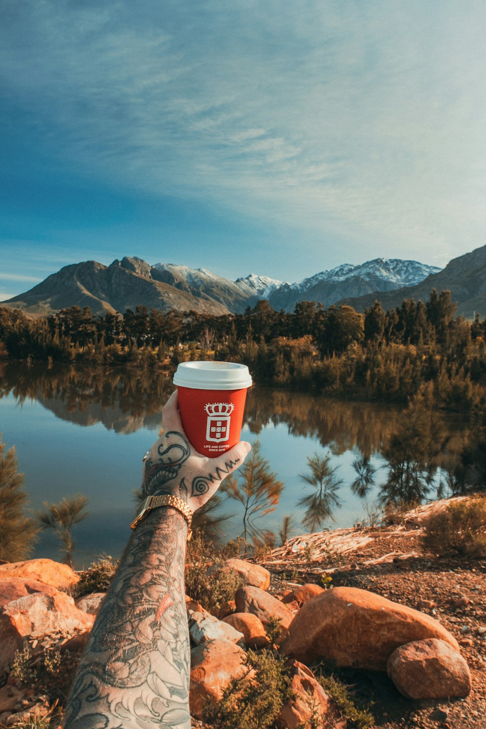 person in brown hiking boots sitting on brown rock near lake during daytime