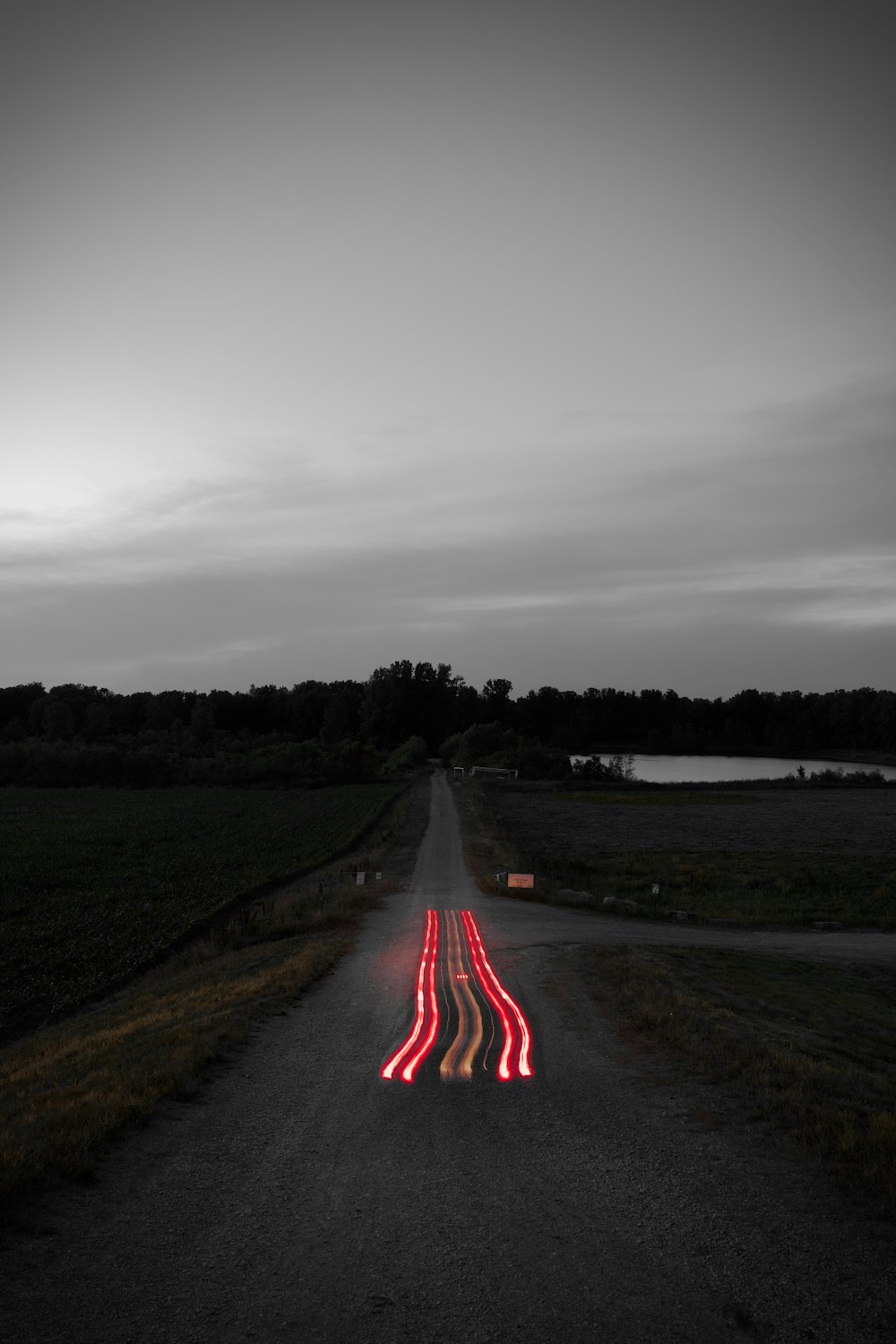 gray asphalt road between green grass field under gray cloudy sky during daytime