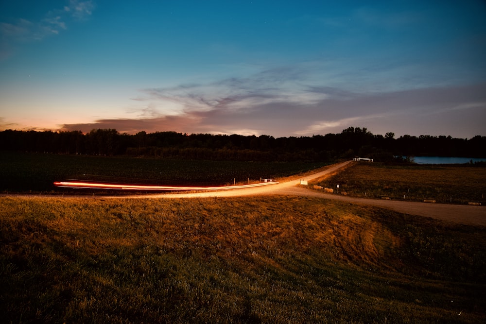 road in the middle of green grass field during sunset