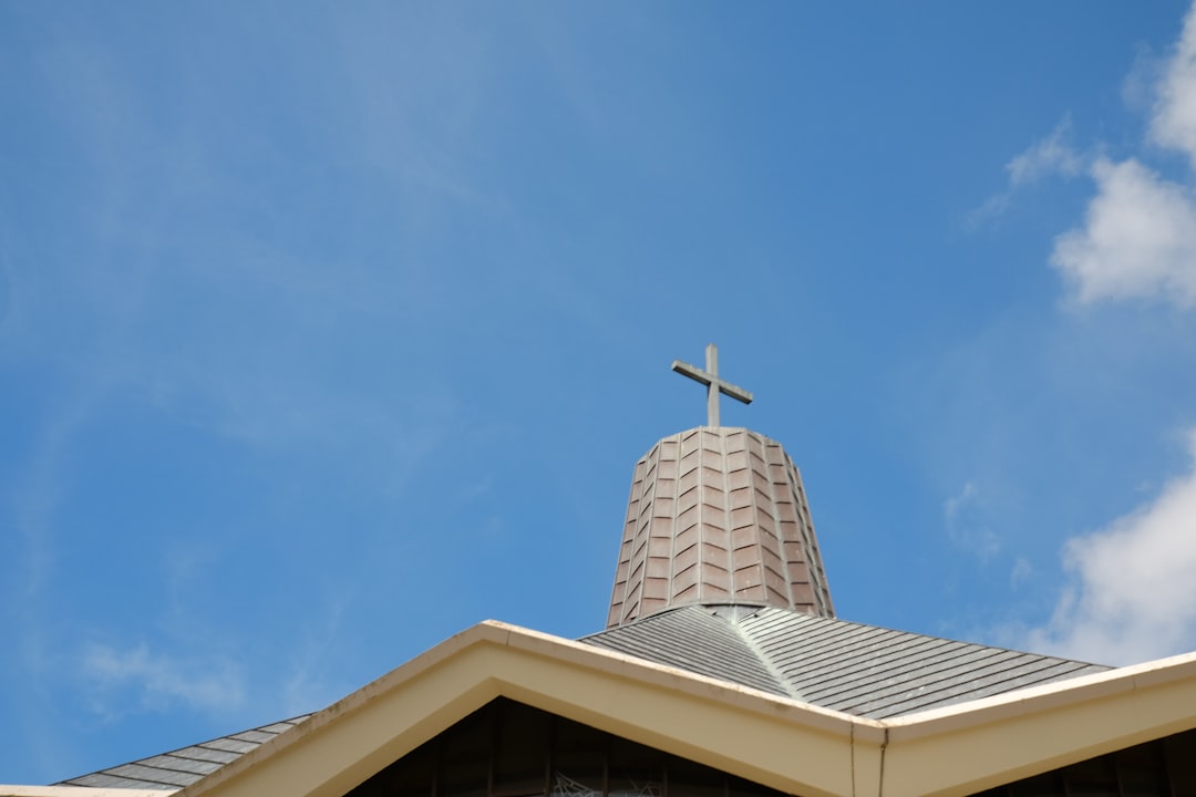 white concrete cross on top of roof under blue sky during daytime