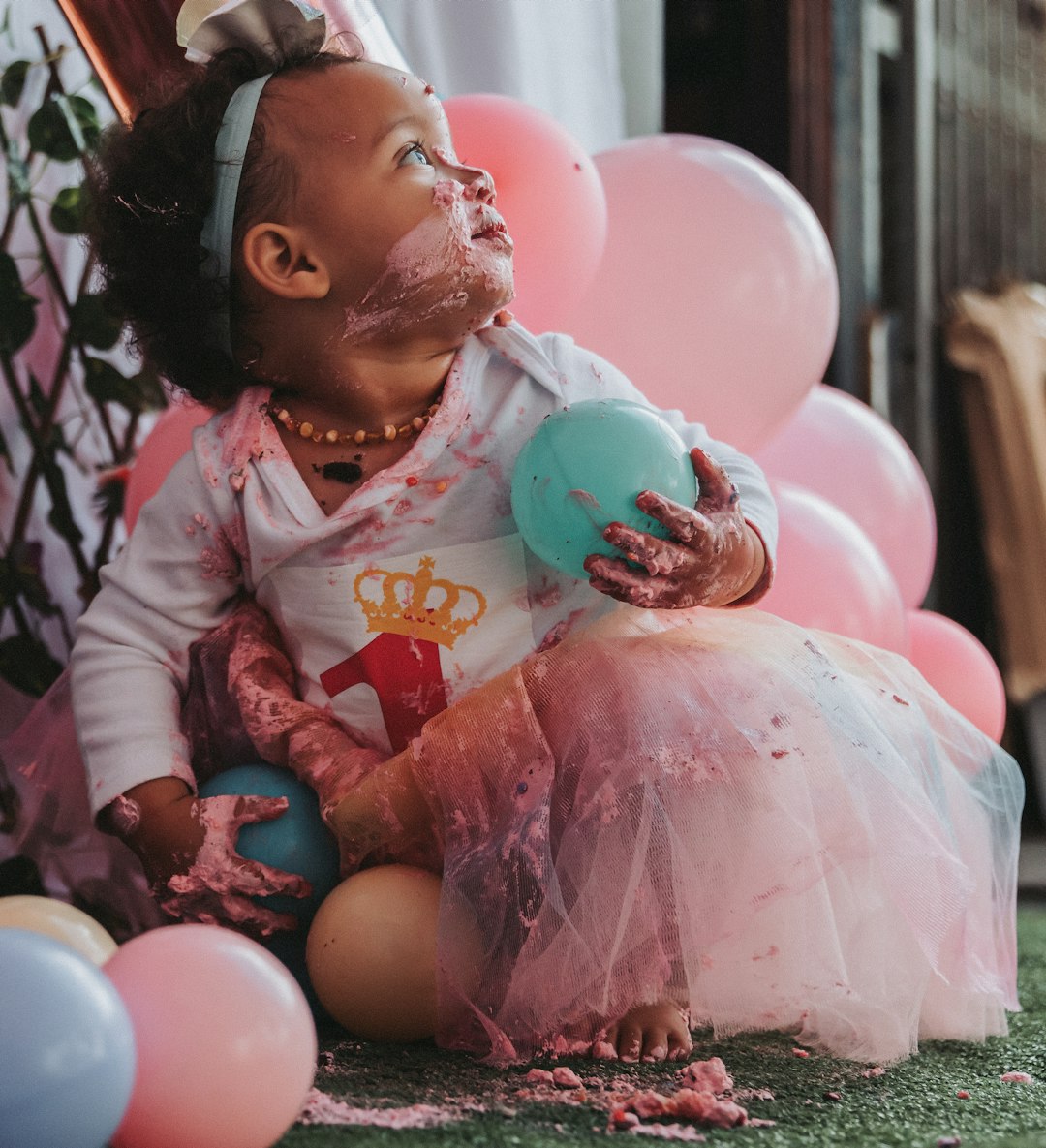 girl in pink and white long sleeve shirt sitting on pink balloons