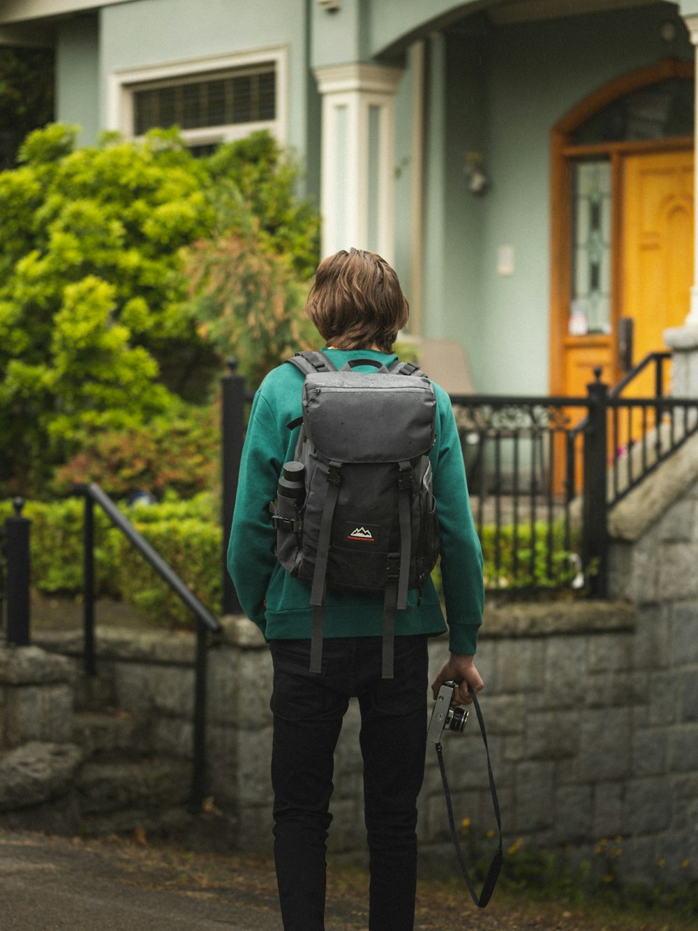 boy in green and black backpack walking on sidewalk during daytime