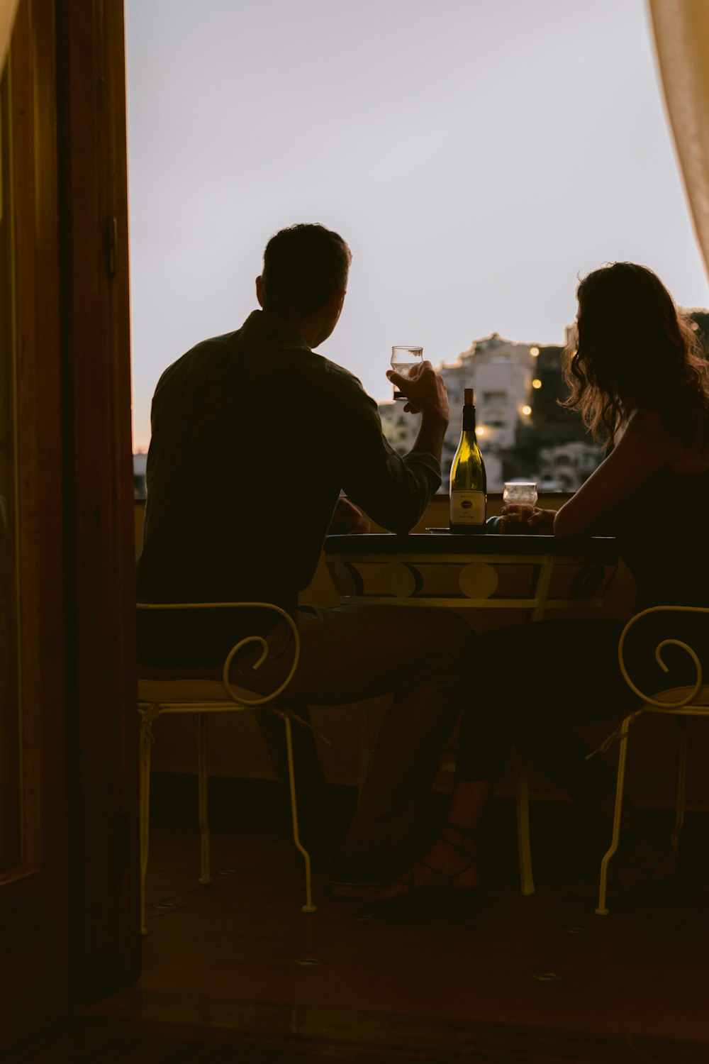 homem e mulher sentados na cadeira na frente da mesa durante o pôr do sol