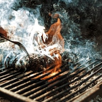 person cooking on grill with fire
