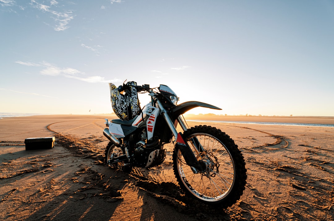 black and gray motorcycle on brown sand under white sky during daytime