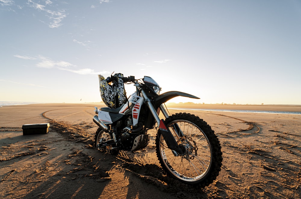 black and gray motorcycle on brown sand under white sky during daytime