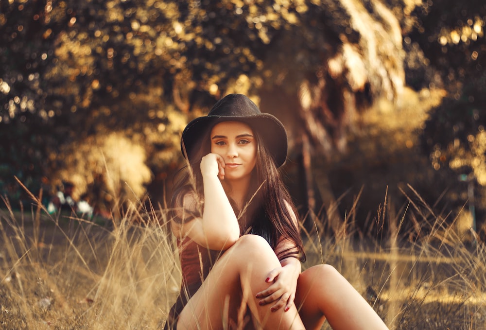 woman in black hat sitting on grass field