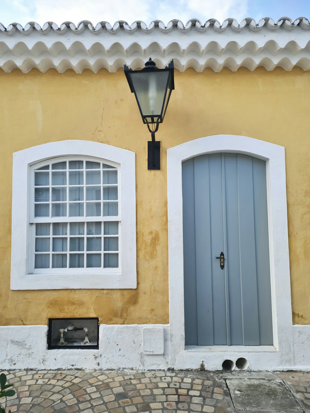 Un edificio amarillo con dos ventanas y una farola