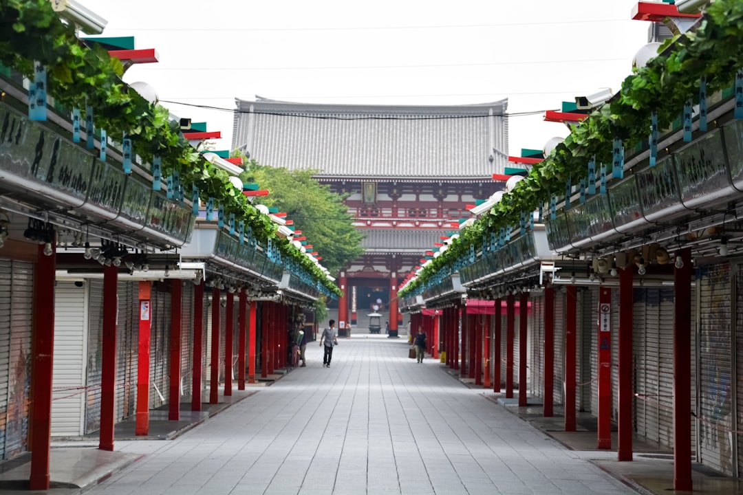 people walking on gray concrete pathway between red and white concrete buildings during daytime