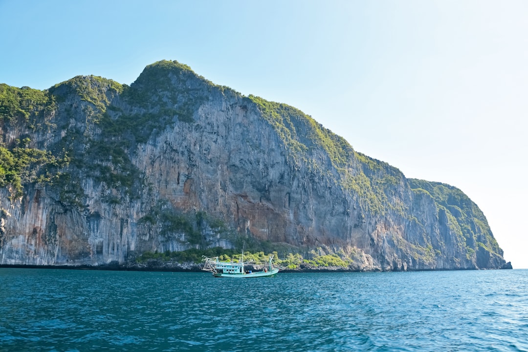 white boat on sea near green and gray mountain during daytime