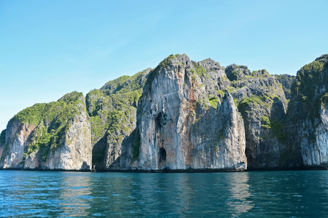 brown and green rock formation on sea during daytime