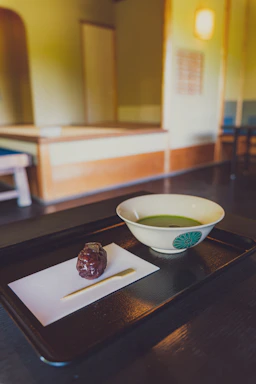 A serene workspace with soft cream tones, a delicate cup of matcha, and traditional Japanese sugar crystals arranged neatly on a wooden tray.