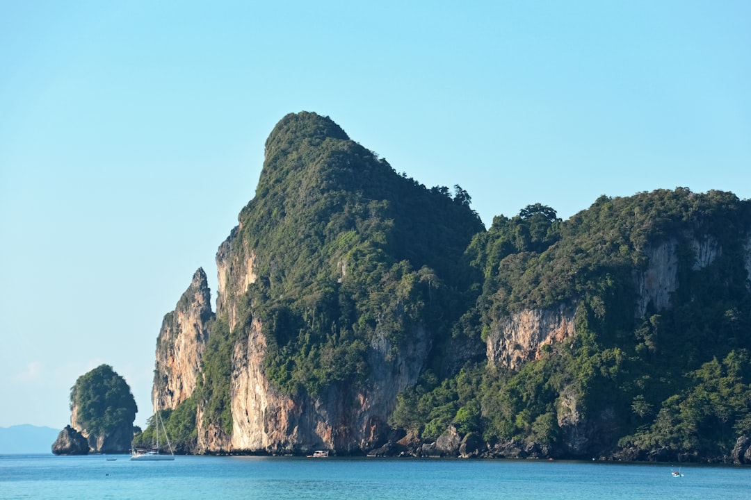 green and brown mountain beside blue sea under blue sky during daytime