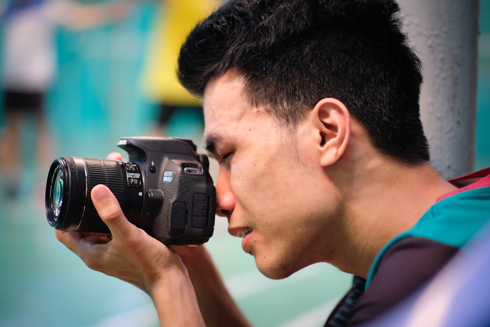 Hombre con camisa azul sosteniendo una cámara DSLR negra