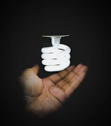 A close-up of hands adjusting a bright LED light bulb shaped like a circus spotlight.